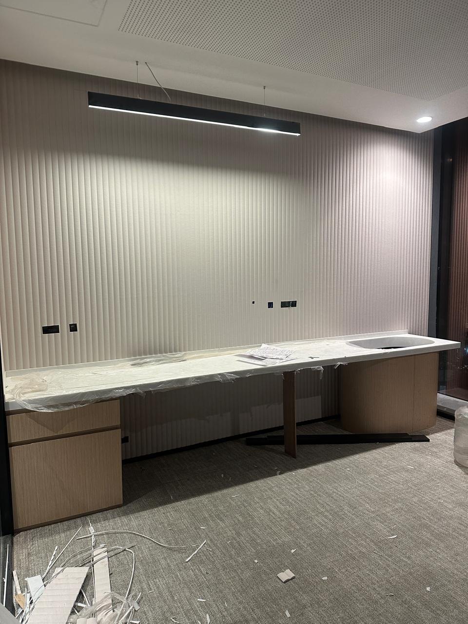 Fluted acoustic wall panelling and a perforated acoustic ceiling during installation