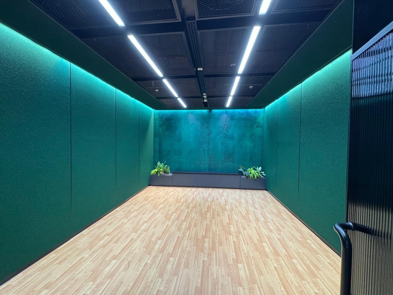 An acoustically treated room finished in teal panels and timber flooring